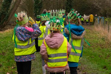 A group of children in paper crowns walk along the Greenway to celebrate Arbor Day.