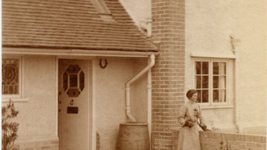An old sepia photo of a Letchworth house with a water butt by the front door.