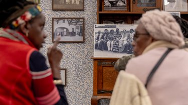 Two people sit in the Museum at One Garden City, looking at old photographs.