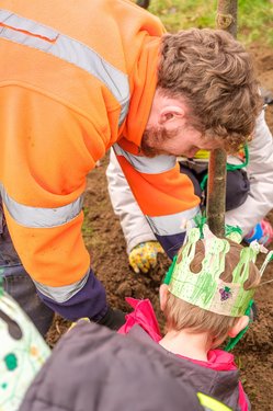 An adult helps children plant trees at the Arbor Day celebrations 2026.