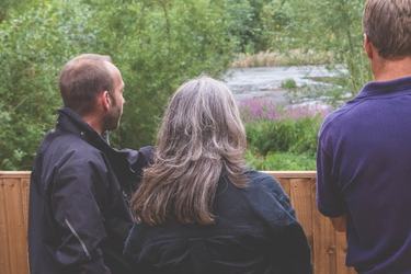 Three people stand by the bird hide at Standalone Farm.
