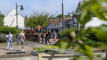 The Wynd in Letchworth, focusing on the community gardens, with a row of shops in the background.