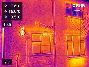 A thermal camera image of a house window, showing how heat escapes from around the window.