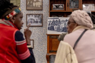 Two people sit in the Museum at One Garden City, looking at old photographs.