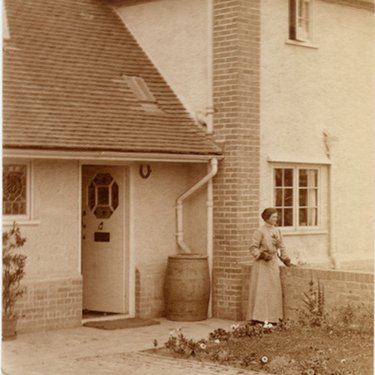 An old sepia photo of a Letchworth house with a water butt by the front door.