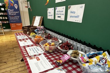 A snack stand with bowls of fruit, crisps and biscuits at Broadway Gallery