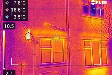 A thermal camera image of a house window, showing how heat escapes from around the window.